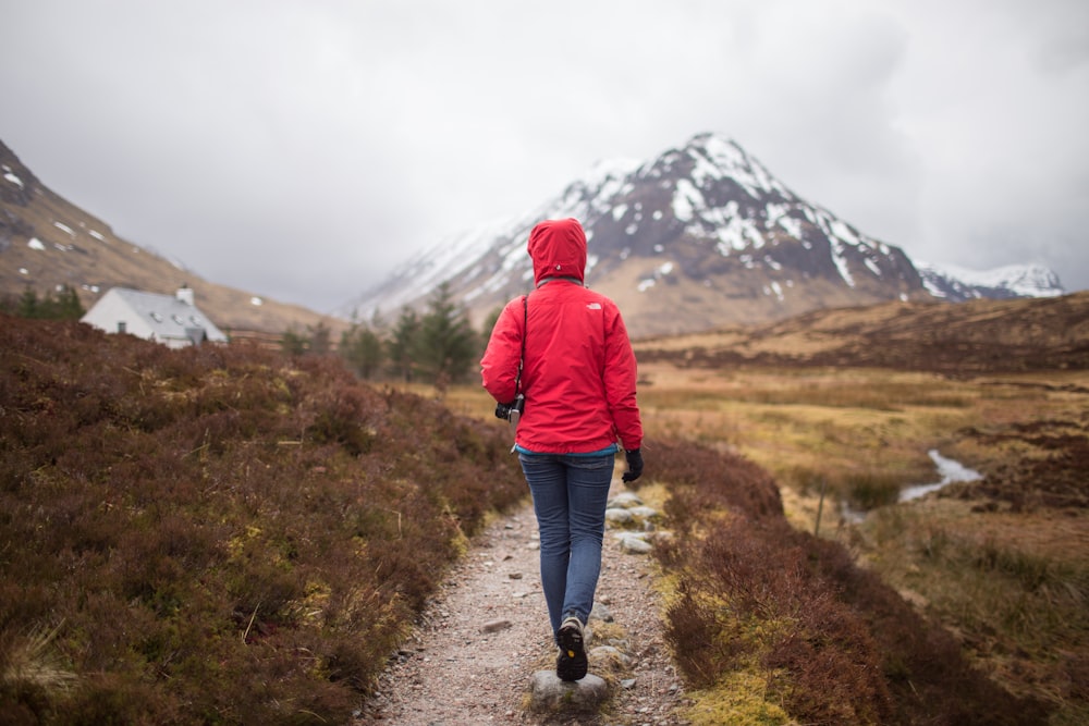 woman walking on brown pathway near house