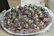 Man presenting a beautifully decorated tray of assorted gourmet brigadeiros with gold accents.