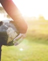 person holding black and brown globe ball while standing on grass land golden hour photography