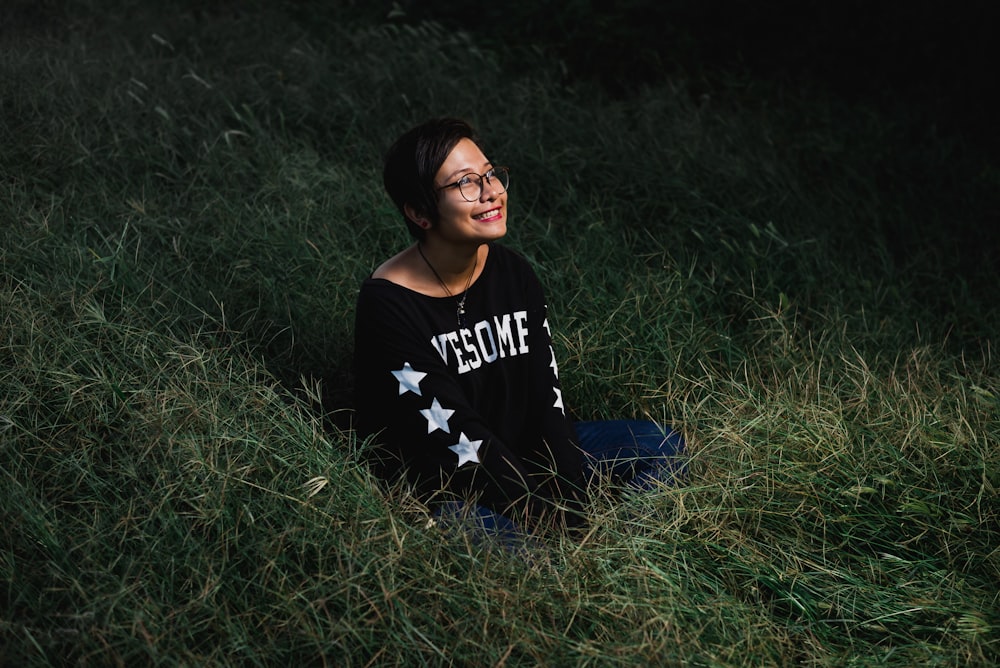 femme assise sur l’herbe souriant et levant les yeux pendant la nuit