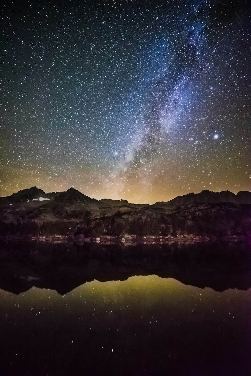 Céu noturno estrelado sobre a montanha pelo lago vítreo