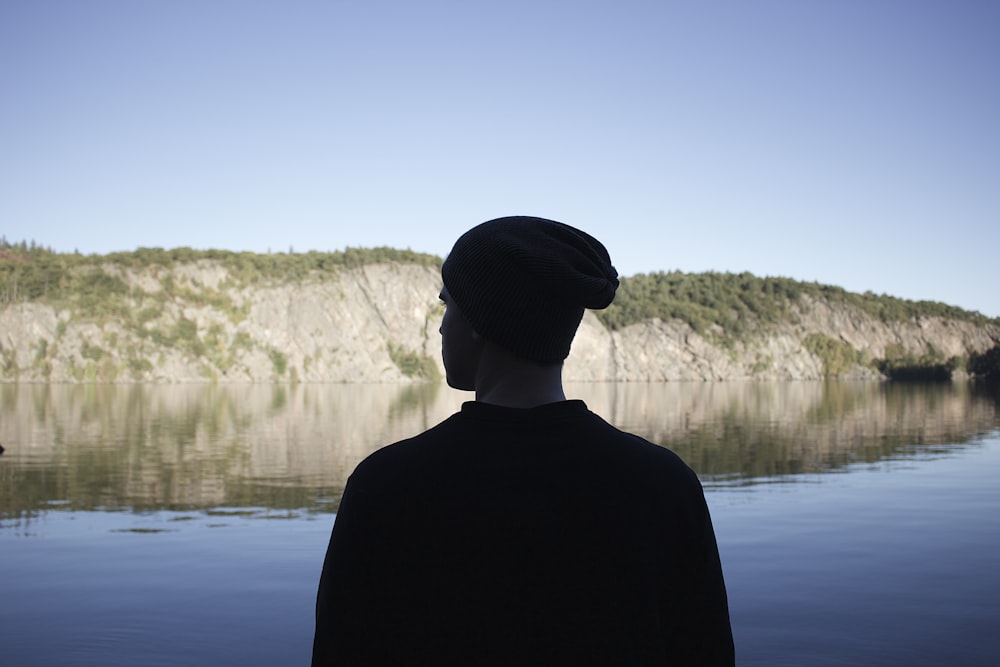 silhouette photography of person beside calm body of water