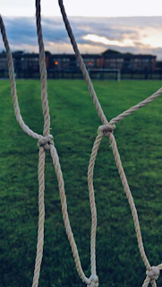 A close-up of a vibrant green soccer net stretched taut against a bright sky.