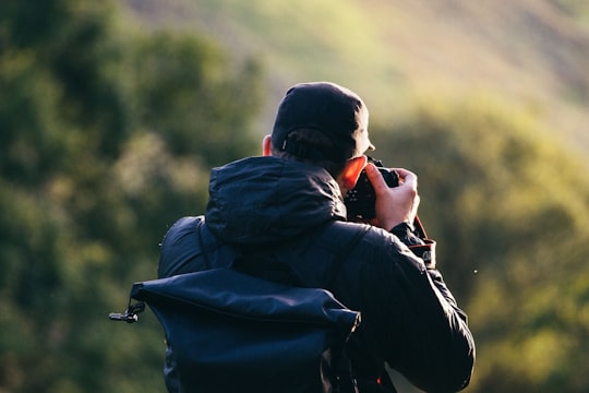 man standing near mountain cliff while taking photo in Snowdon United Kingdom