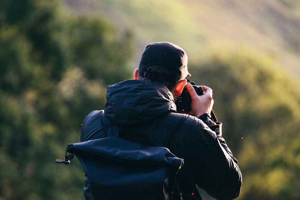 Hombre de pie cerca del acantilado de la montaña mientras toma una foto