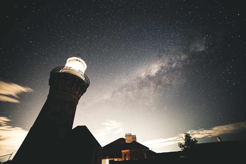 silhouette photography of house beside lighthouse