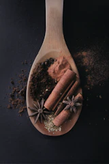 A rustic wooden spoon filled with a mix of dried herbs and spices, evoking the essence of Haitian cooking.
