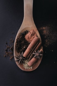 Freshly ground spices in wooden spoons with aromatic herbs scattered around.