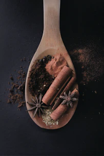 A rustic wooden spoon filled with a mix of dried herbs and spices, evoking the essence of Haitian cooking.