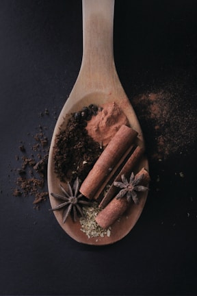 A rustic wooden spoon resting on a bowl of vibrant mixed spices.