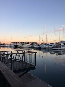 A serene marina with luxury yachts docked alongside wooden piers at sunset.