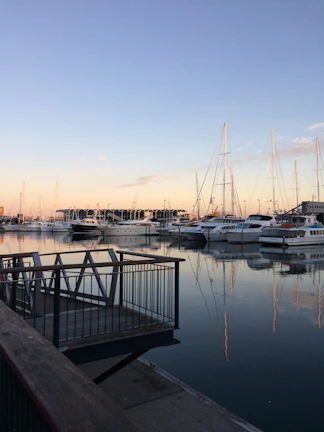 A serene marina at sunset with yachts docked under a clear blue sky.