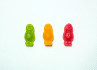 Red, Orange, Green Gummy bears next to each  other