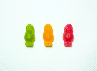 1 green, 1 orange and 1 red gummy bear next to each other