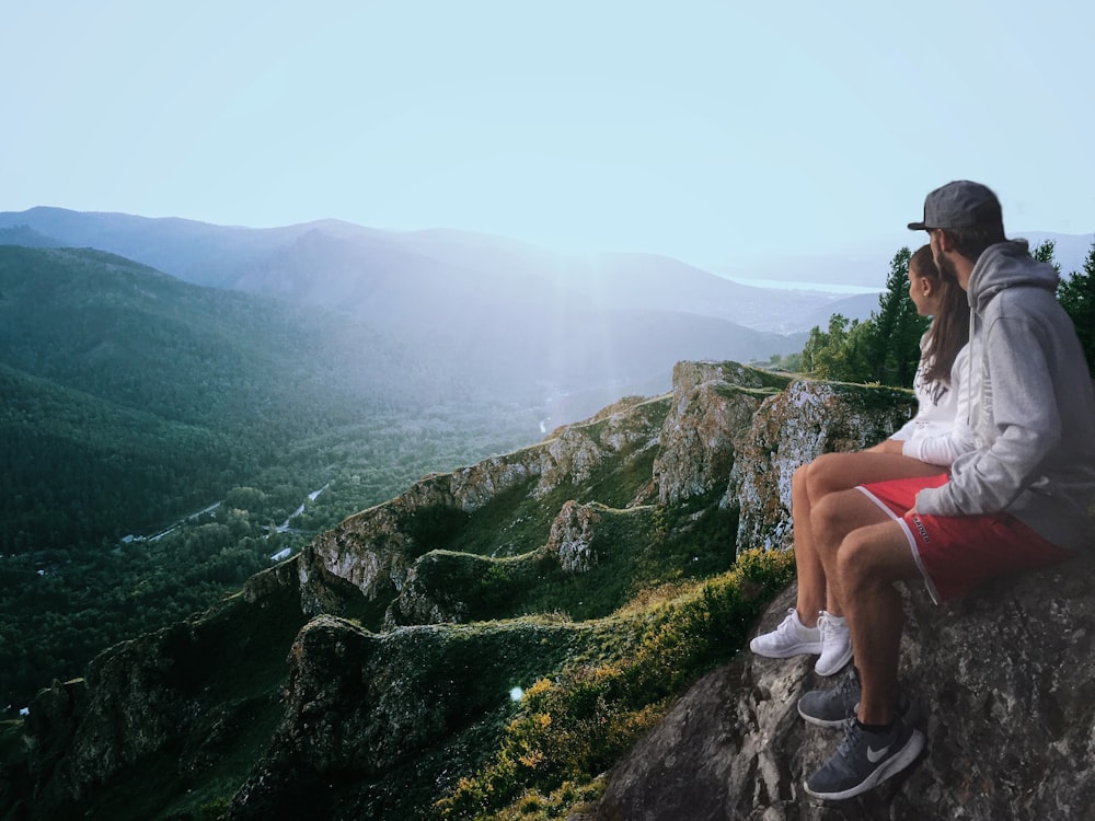 couple assis sur le bord tout en regardant les montagnes