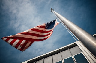 low-angle photo of U.S. flag placed on gray pole