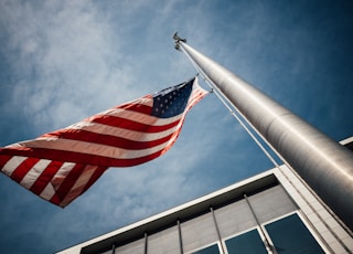 low-angle photo of U.S. flag placed on gray pole