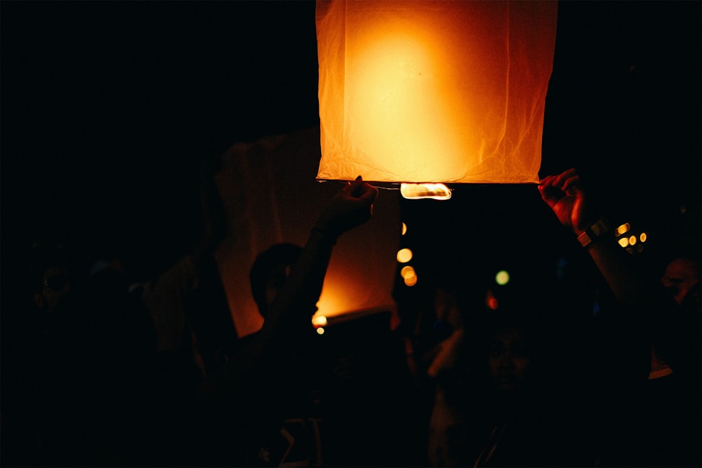 a person holding a lit up lantern in the dark