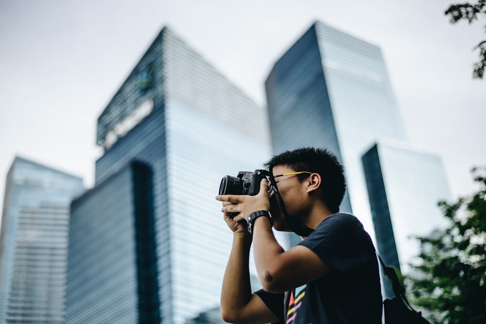 man wearing black t-shirt holding DSLR camera