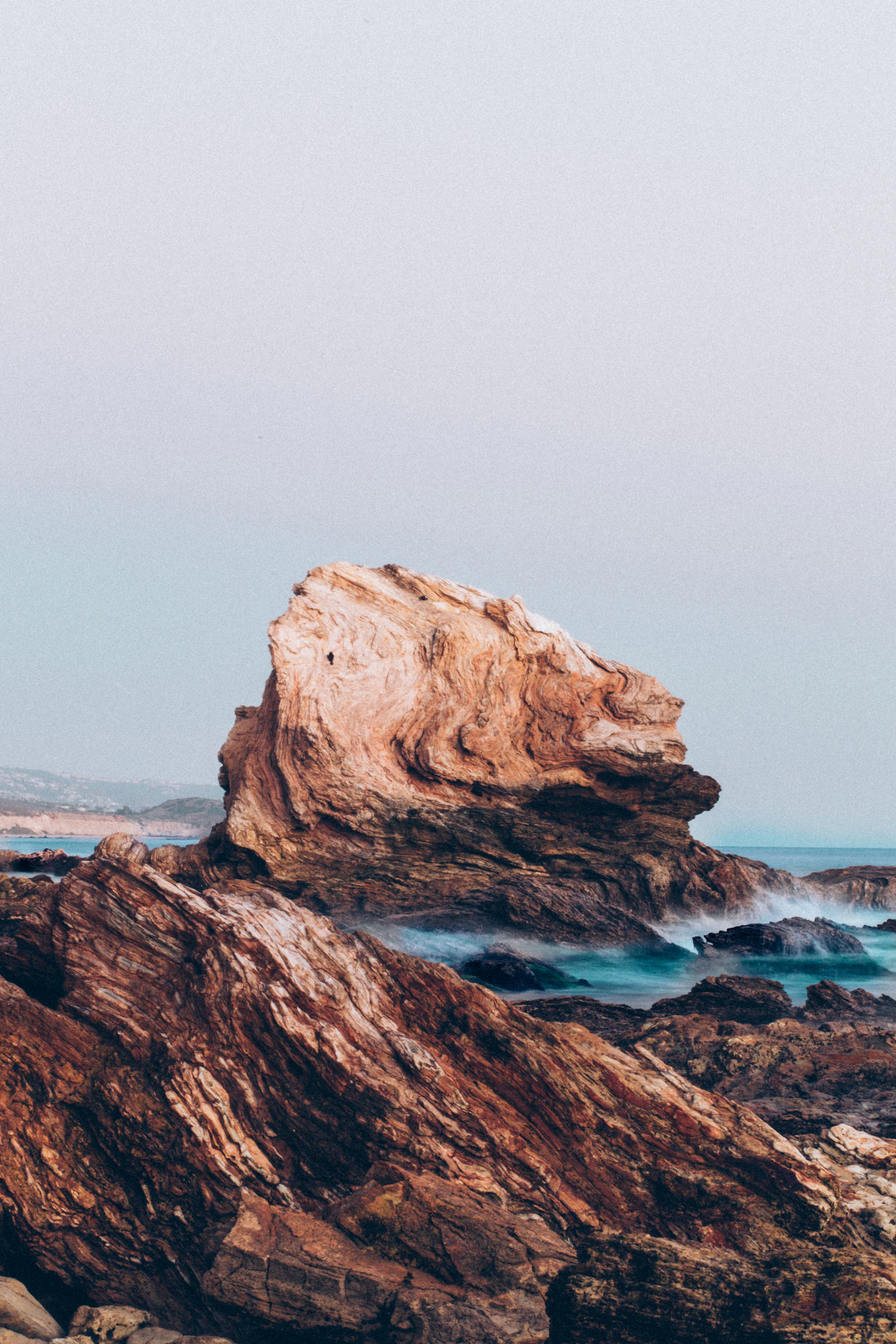 Sandstone rocks at the water's edge under a pale morning sky