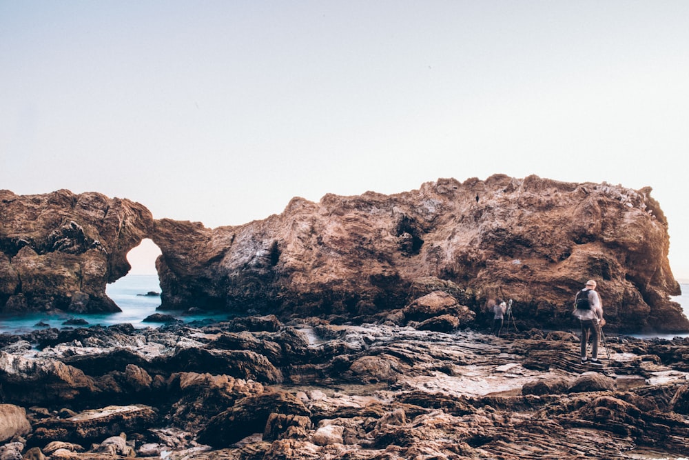 person standing on rock near body of water during daytime