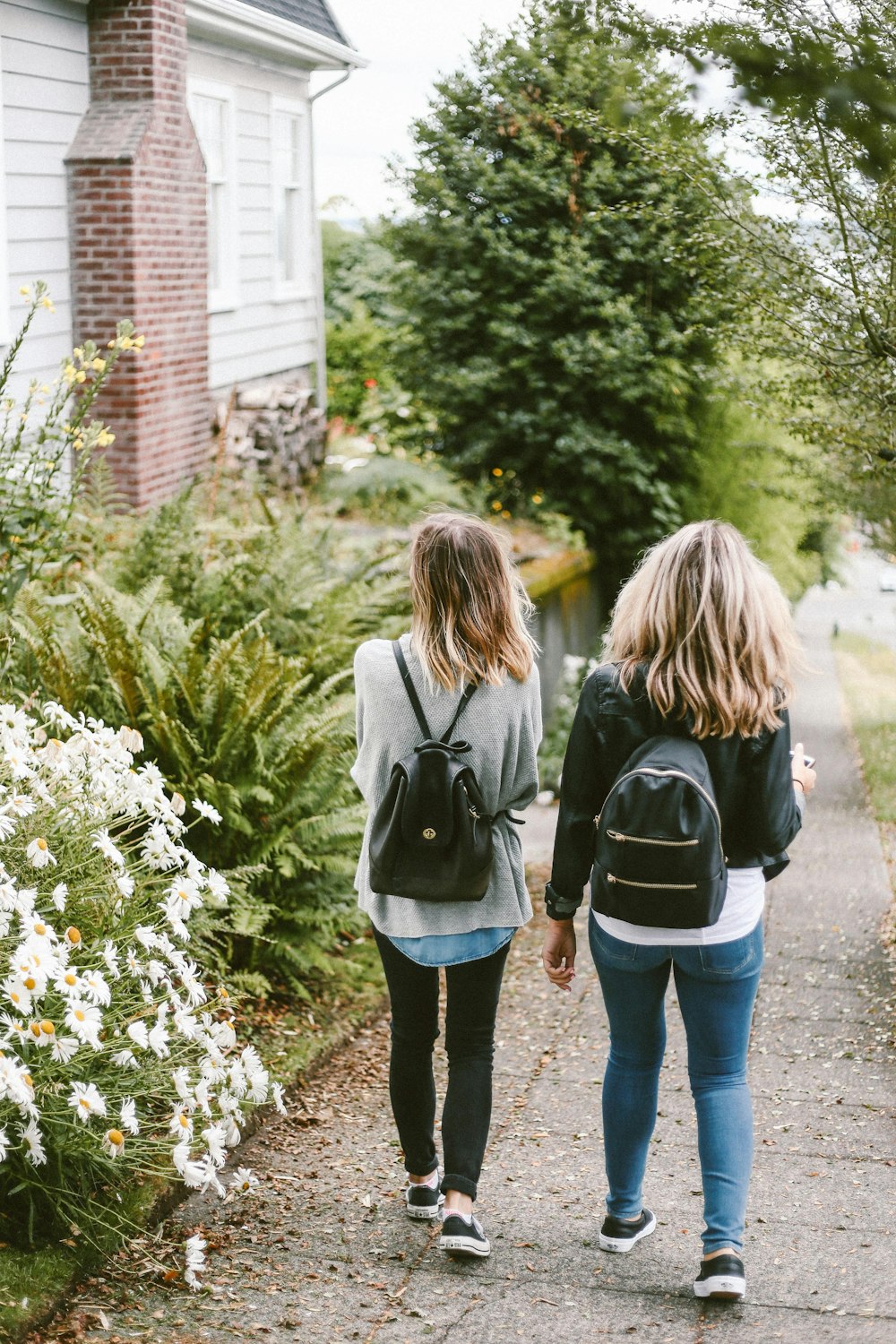 deux dames marchant sur le trottoir avec des sacs à dos noirs