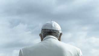 person wearing white cap looking down under cloudy sky during daytime