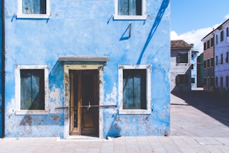 Bold blue exterior wall of a commercial building being painted on a sunny day.
