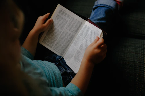 Close-up of a child reading a book with a brand ad on the front page.