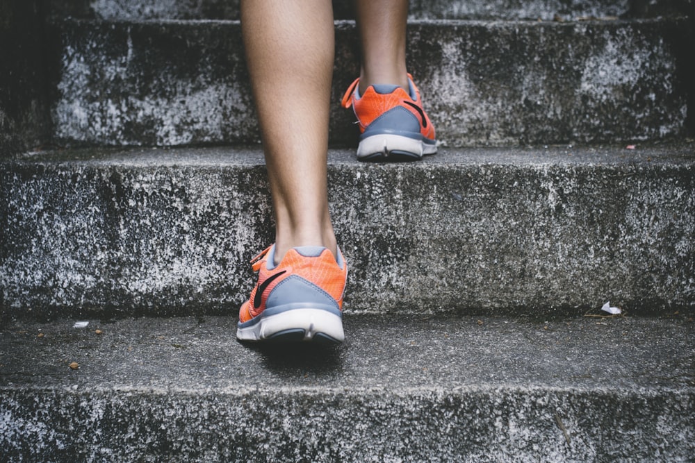 Persona che indossa scarpe Nike arancioni e grigie che cammina su scale di  cemento grigio photo – Photo Santé Gratuite sur Unsplash