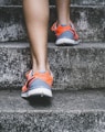 person wearing orange and gray Nike shoes walking on gray concrete stairs