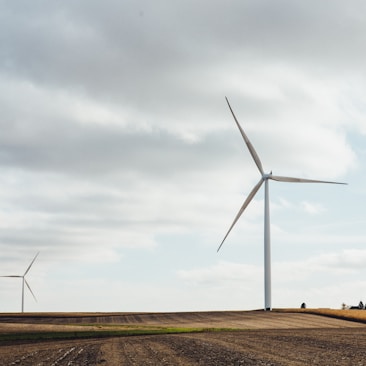 two white windmills on brown field during daytime