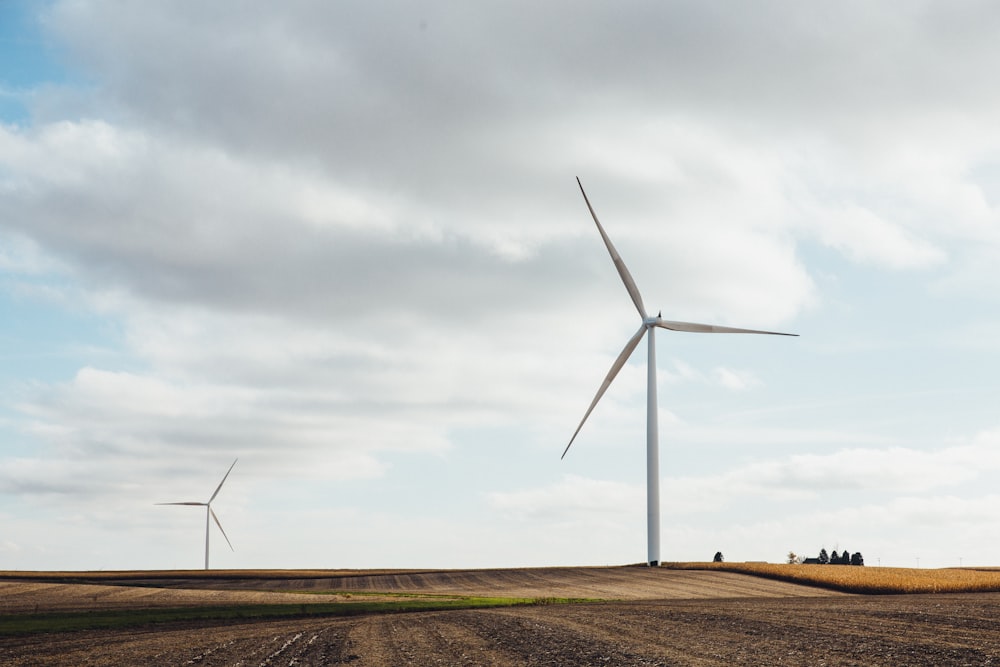 two white windmills on brown field during daytime