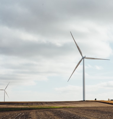 two white windmills on brown field during daytime