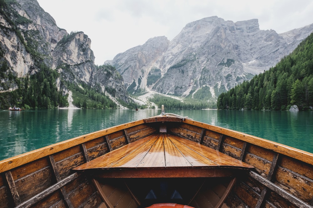 brown wooden boat moving towards the mountain