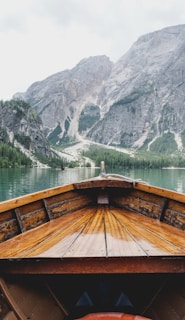 brown wooden boat moving towards the mountain