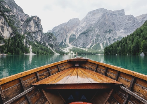 brown wooden boat moving towards the mountain