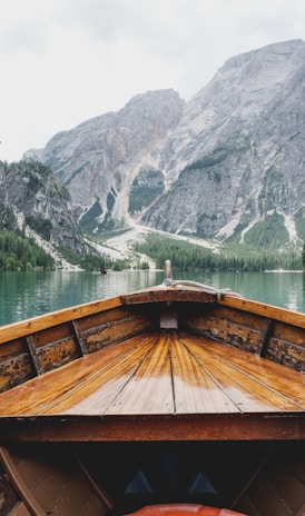 brown wooden boat moving towards the mountain