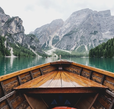 brown wooden boat moving towards the mountain