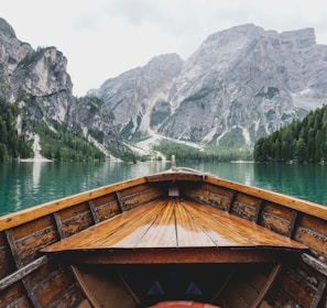 brown wooden boat moving towards the mountain