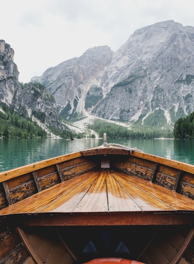 brown wooden boat moving towards the mountain