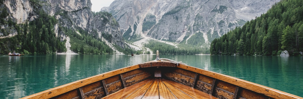 brown wooden boat moving towards the mountain