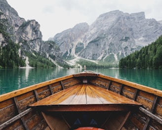 brown wooden boat moving towards the mountain