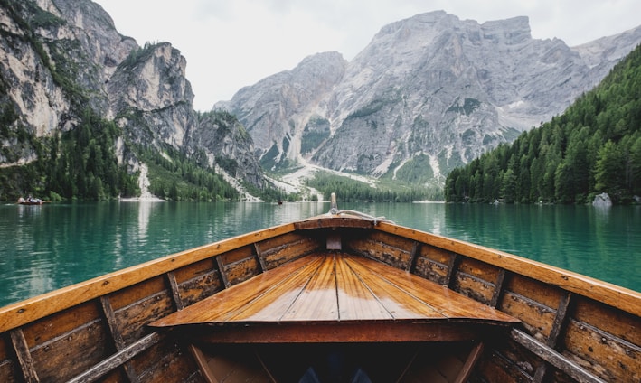 brown wooden boat moving towards the mountain