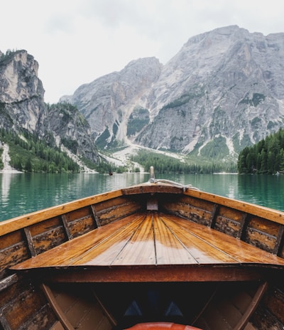 brown wooden boat moving towards the mountain