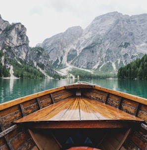 brown wooden boat moving towards the mountain