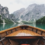 brown wooden boat moving towards the mountain