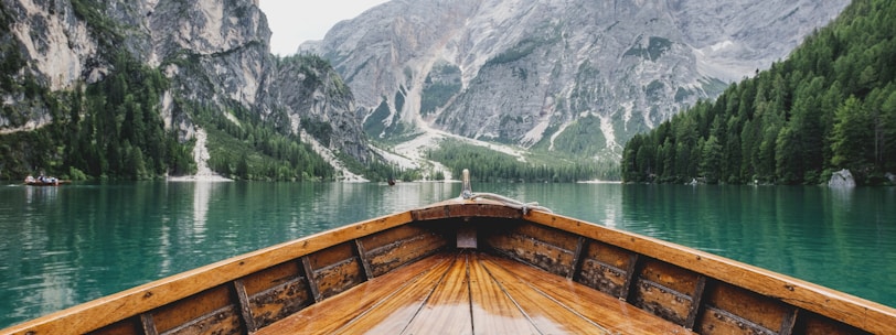 brown wooden boat moving towards the mountain