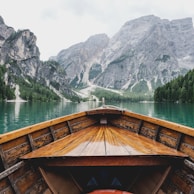 brown wooden boat moving towards the mountain