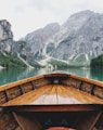 brown wooden boat moving towards the mountain